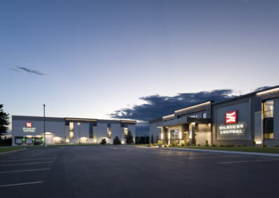 Modern concrete distribution center exterior and corporate office with steel roofing and multiple loading docks at dusk